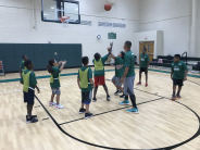 Co-ed summer basketball camp children and coach playing basketball